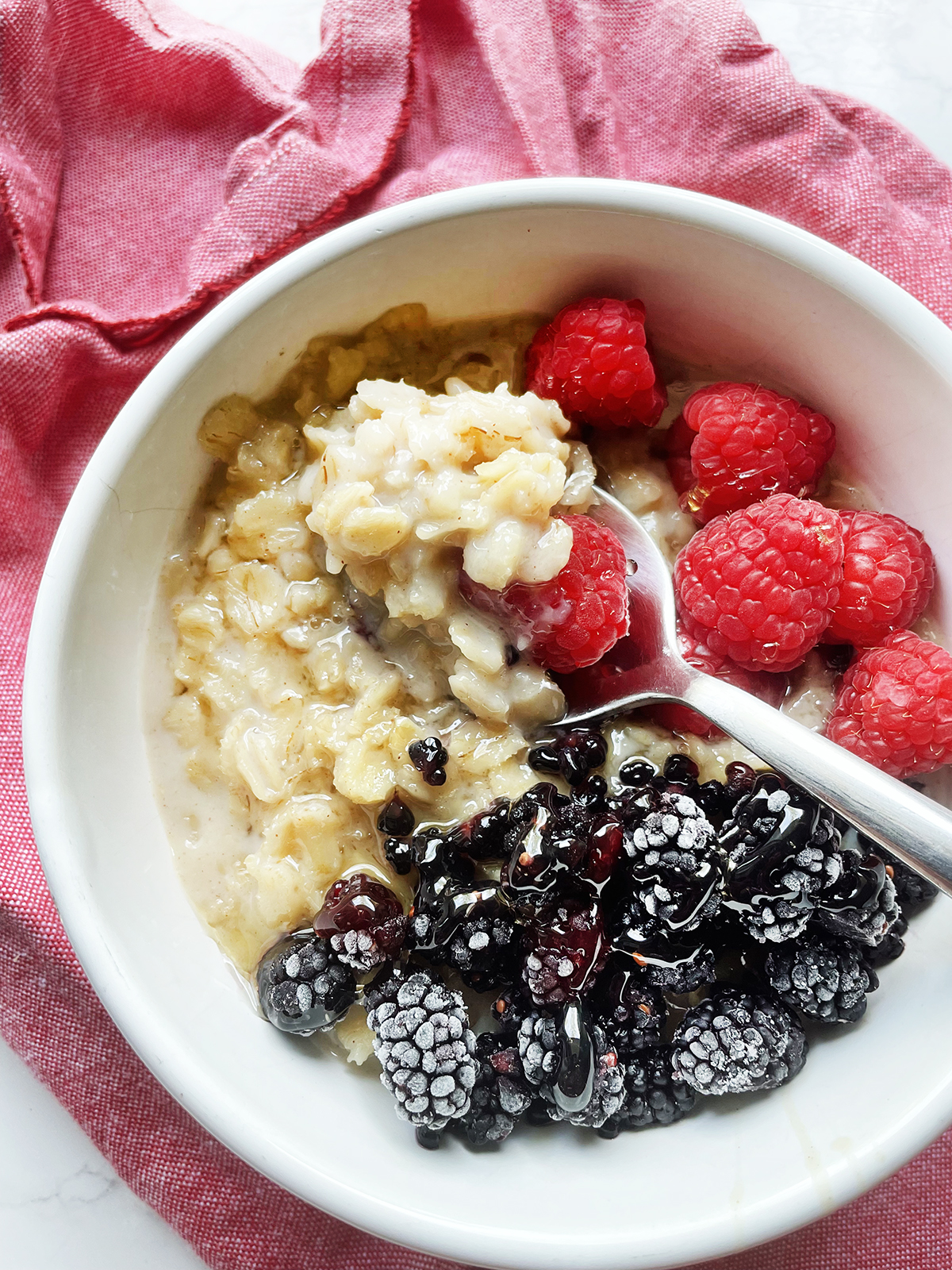 Bowl of oatmeal with berries with a spoon stuck into the mix.