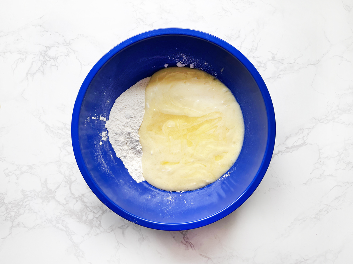 Batter coming together in a blue bowl for muffins.