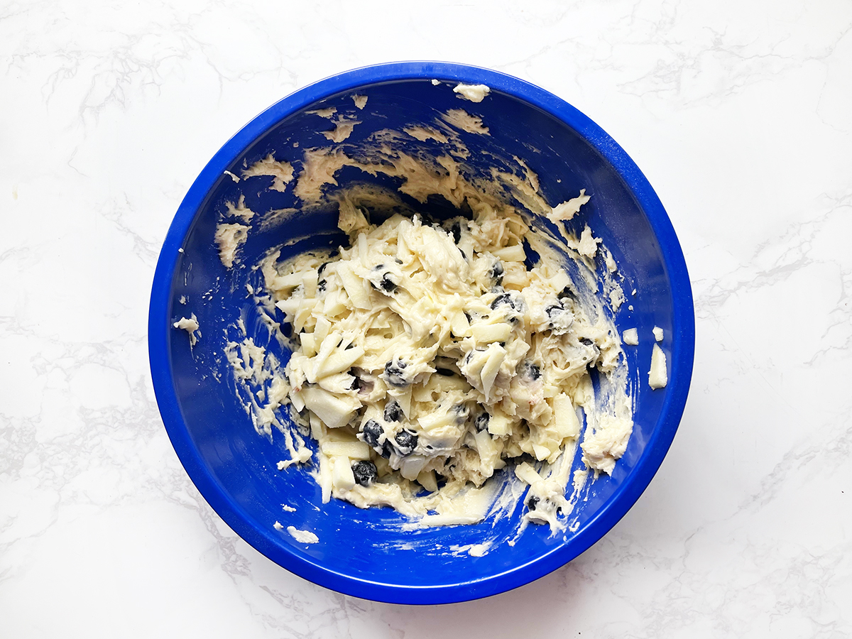 Muffin batter with shredded apples and blueberries folded in.