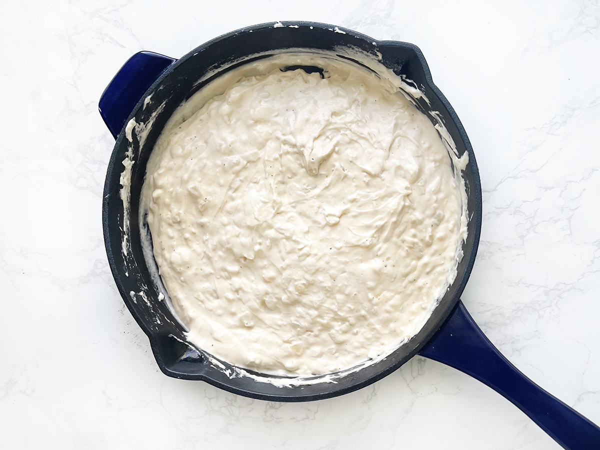 Cast iron skillet with a creamy mixture inside.