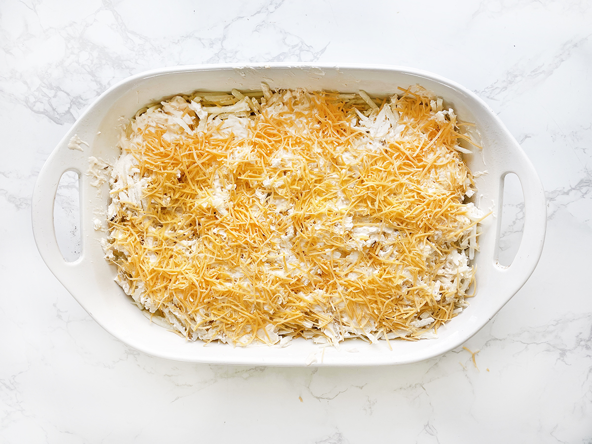 Cheesy casserole with potatoes in baking dish before going in the oven.