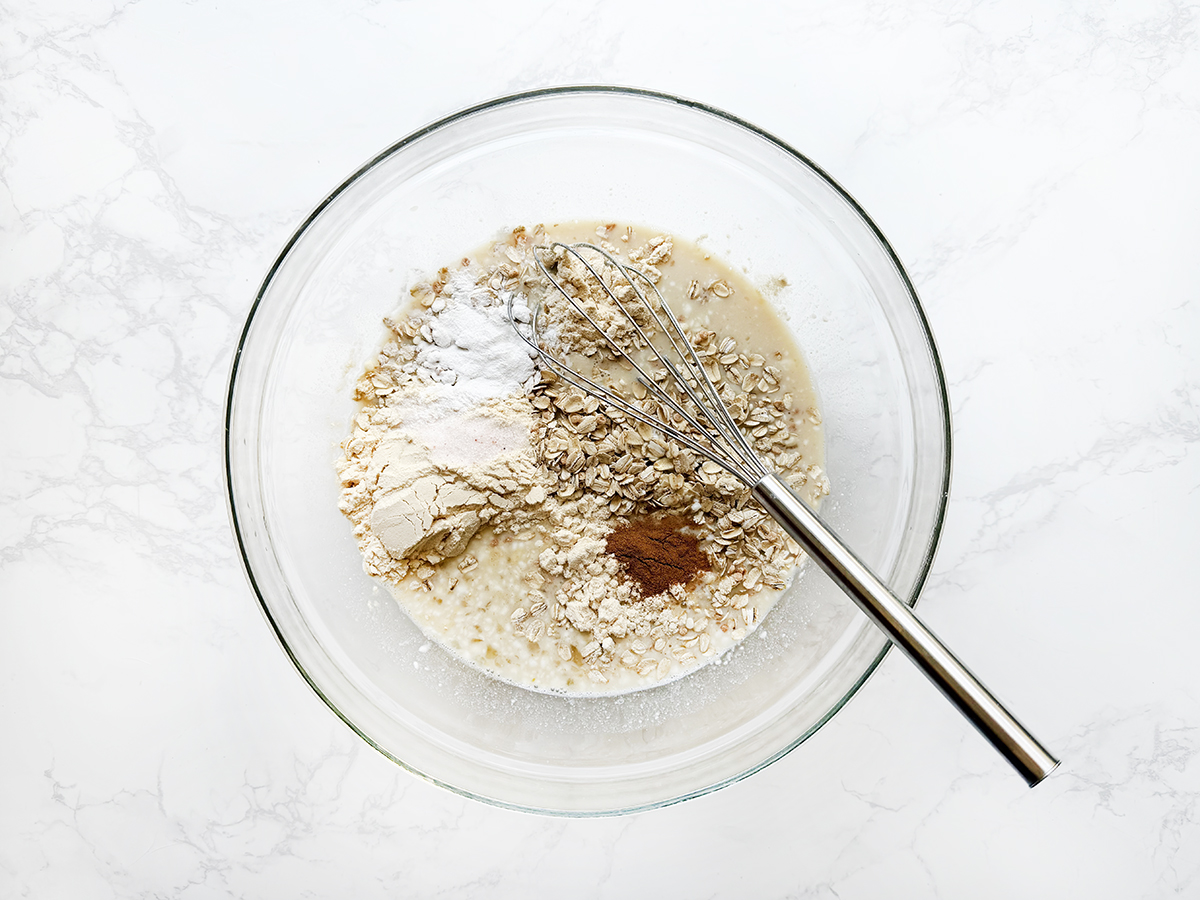 Dry ingredients in a glass bowl with a whisk sticking out.