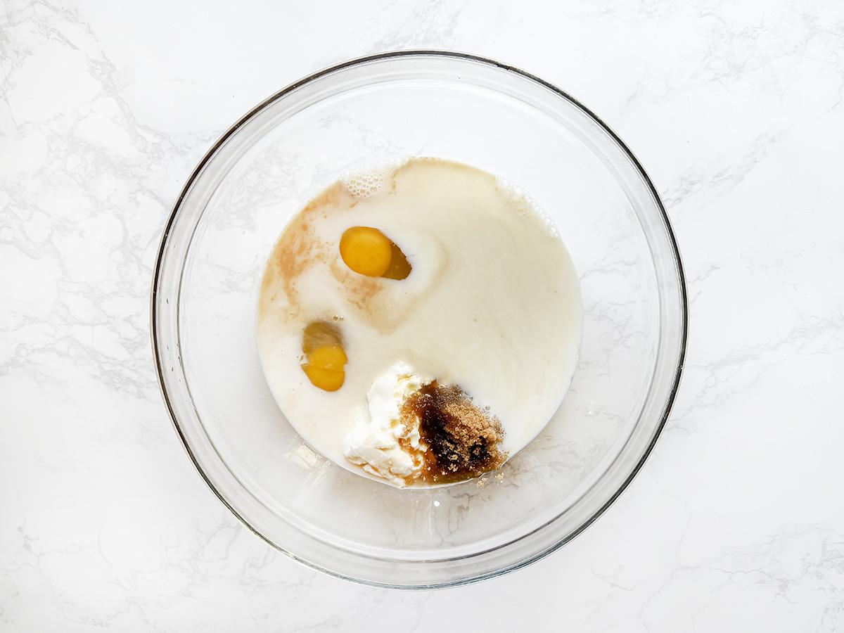 Wet ingredients in a bowl, including eggs, milk and sugar.