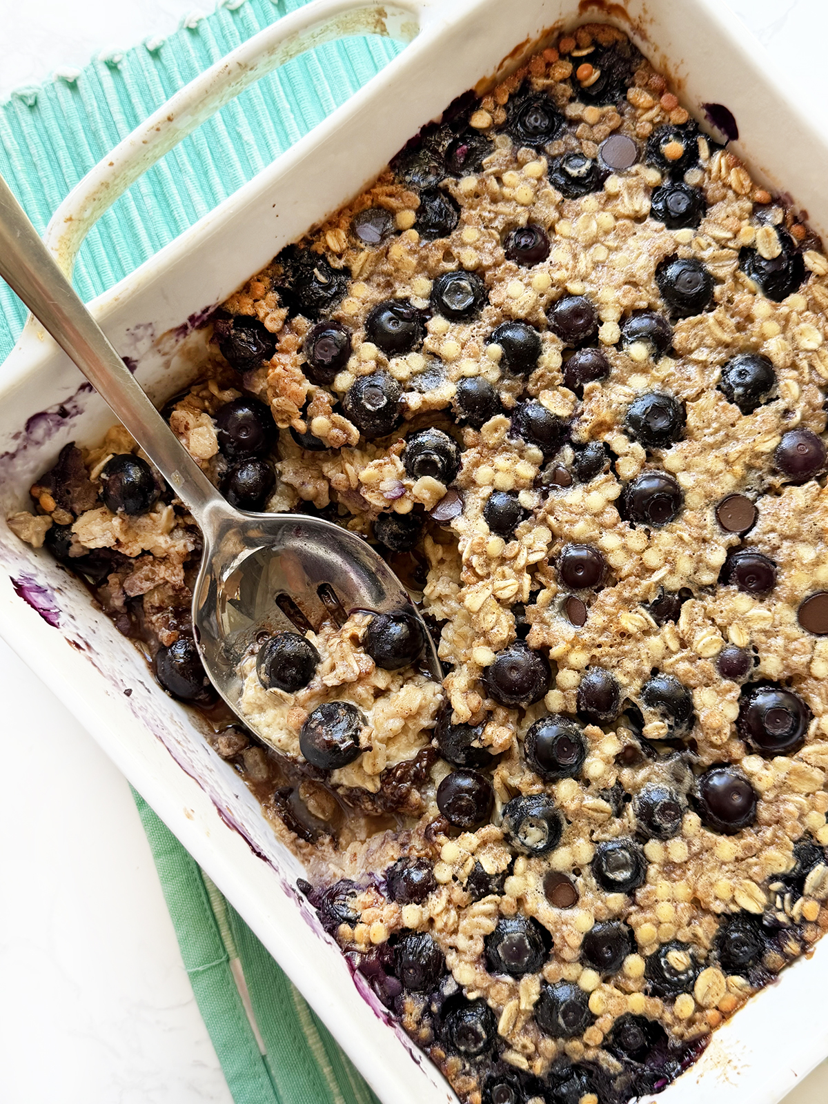 Protein baked oatmeal in a baking dish, topped with blueberries and chocolate chips.