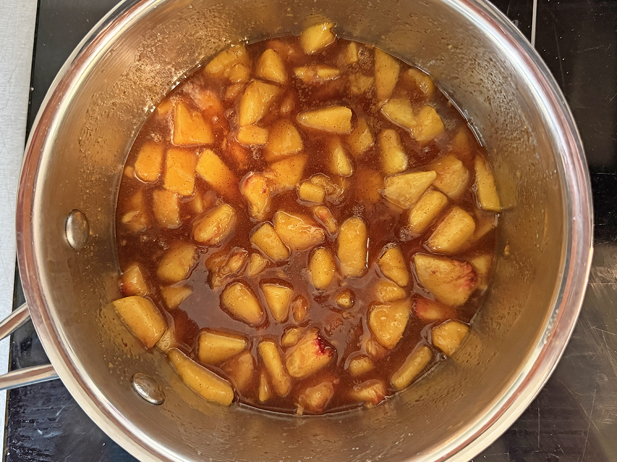 Peach sauce thickened in a saucepan.