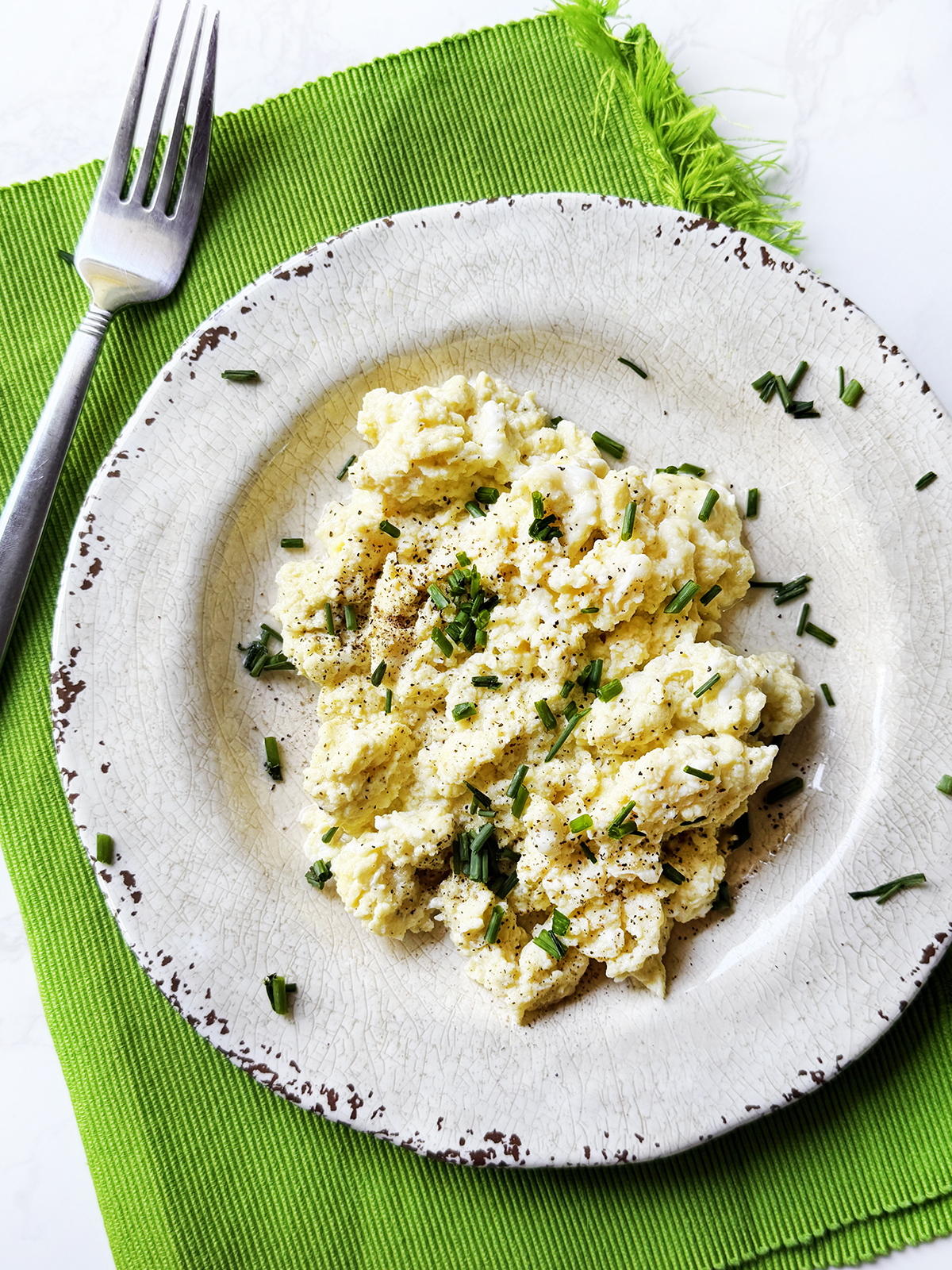 Serving of cottage cheese scrambled eggs topped with chives.